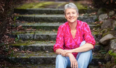 Gitte Lassen terapeut og coach for sensitive kvinder med stress sidder på en rustik trappe
