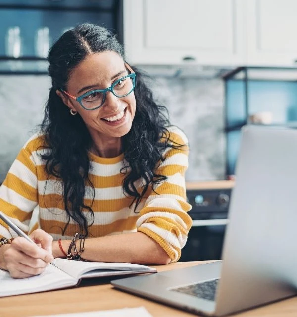 Kvinde deltager på online foredrag og tager noter